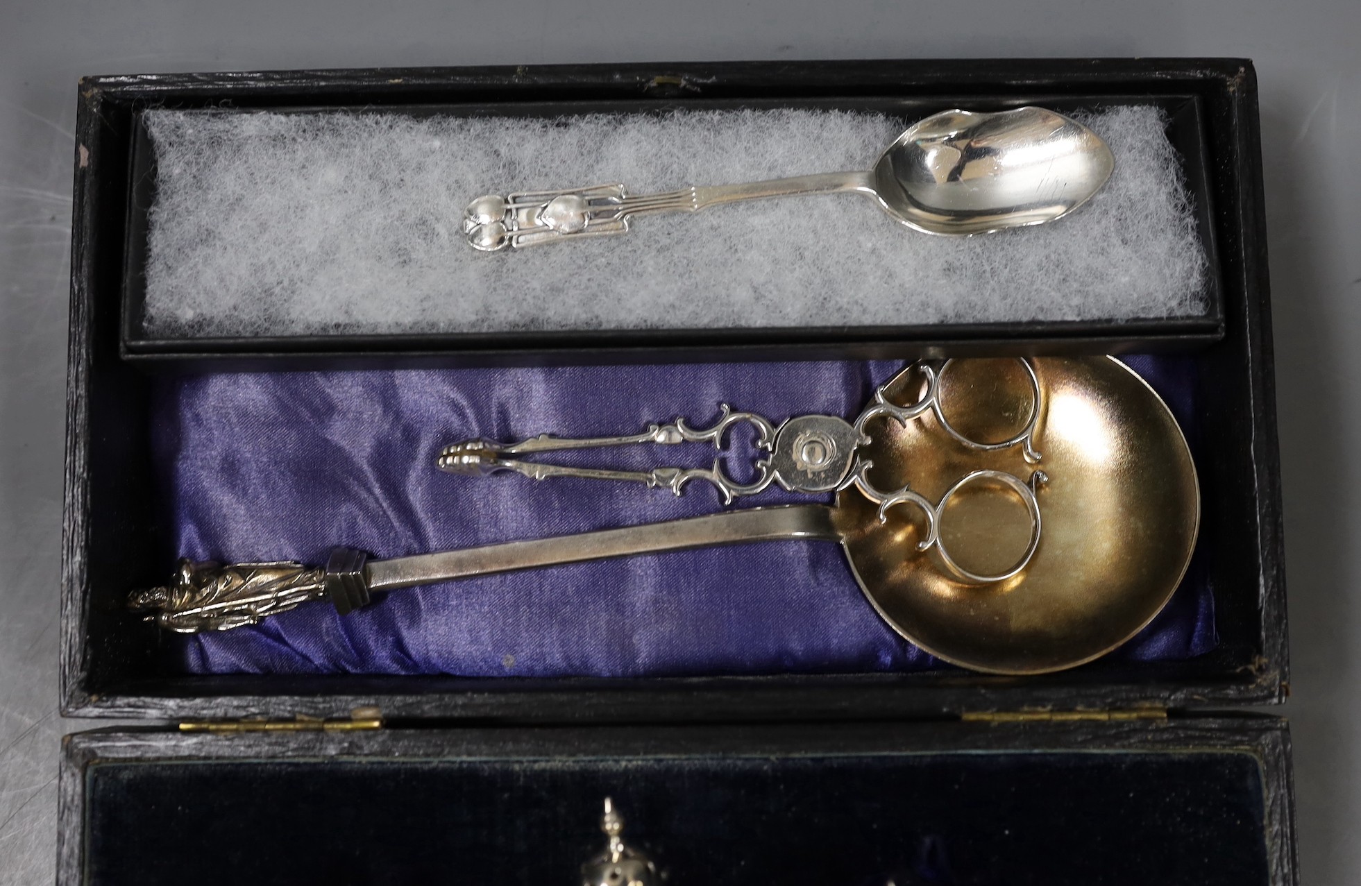 A cased George V silver three piece condiment set, lacking spoons, a 1930's Arts & Crafts sile r spoon by Liberty & Co, a Victorian silver apostle spoon and a pair of 18th century silver sugar nips.